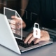 person typing on a computer with a lock graphic and document graphic overlay